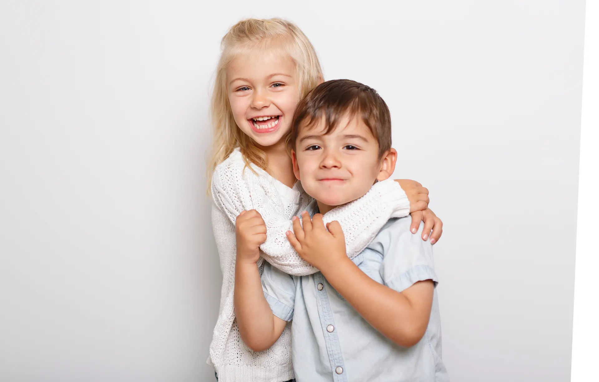 Ein blondes Mädchen umarmt einen Jungen