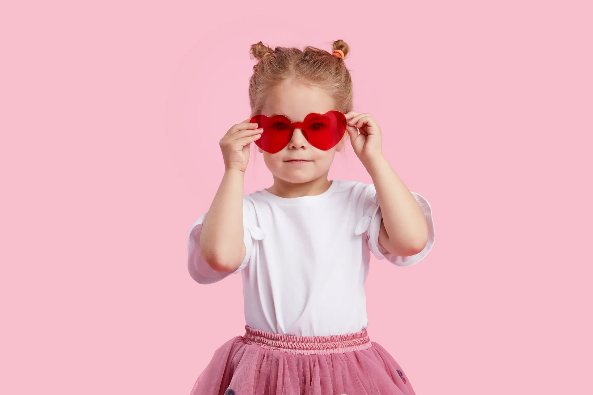 Mädchen mit Herzbrille vor rosa Hintergrund