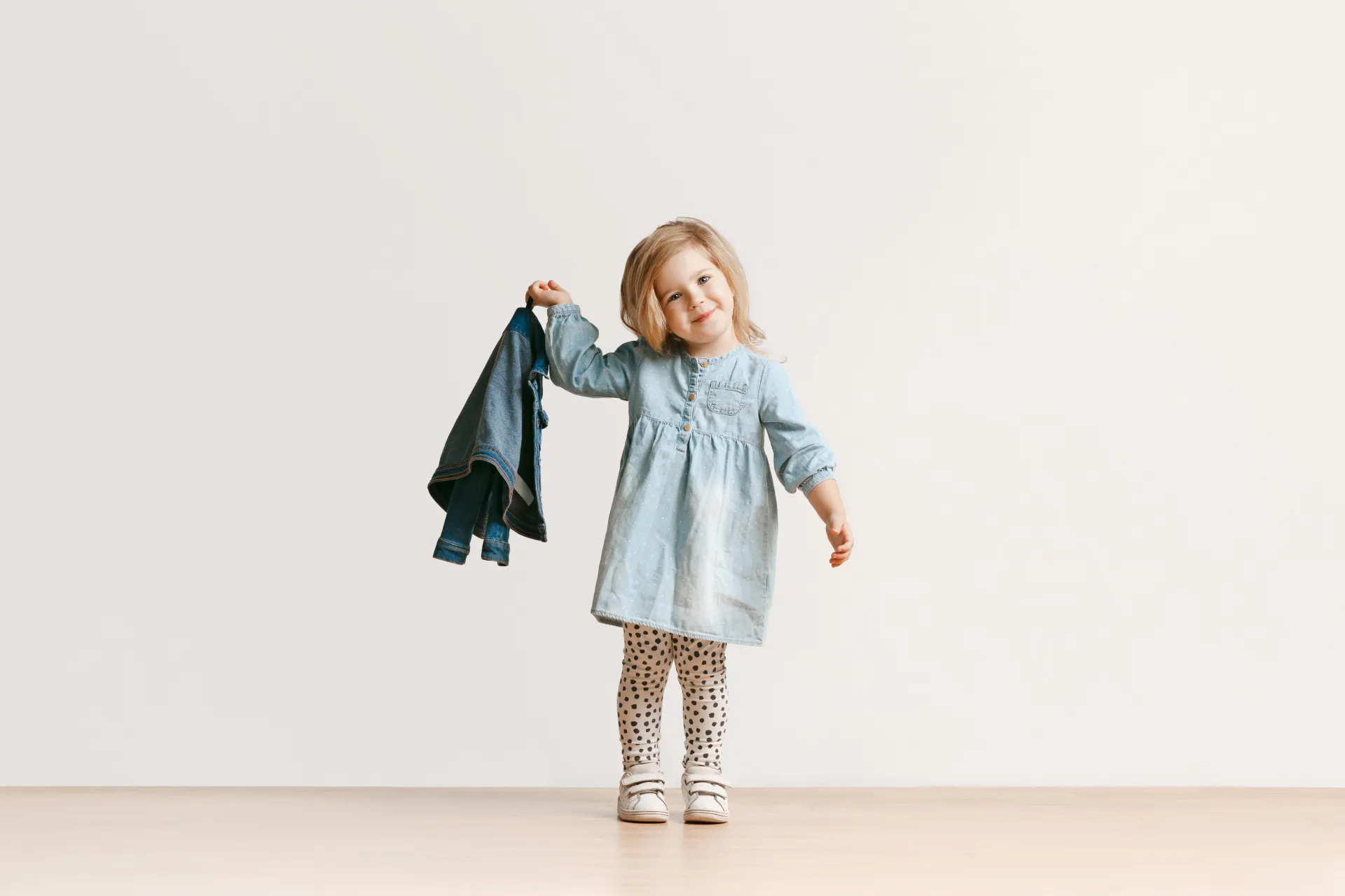 Ein kleines Mädchen hält eine Jeansjacke