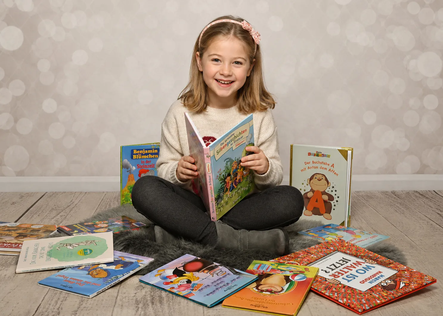 Lächelndes Mädchen liest Buch umgeben von Büchern