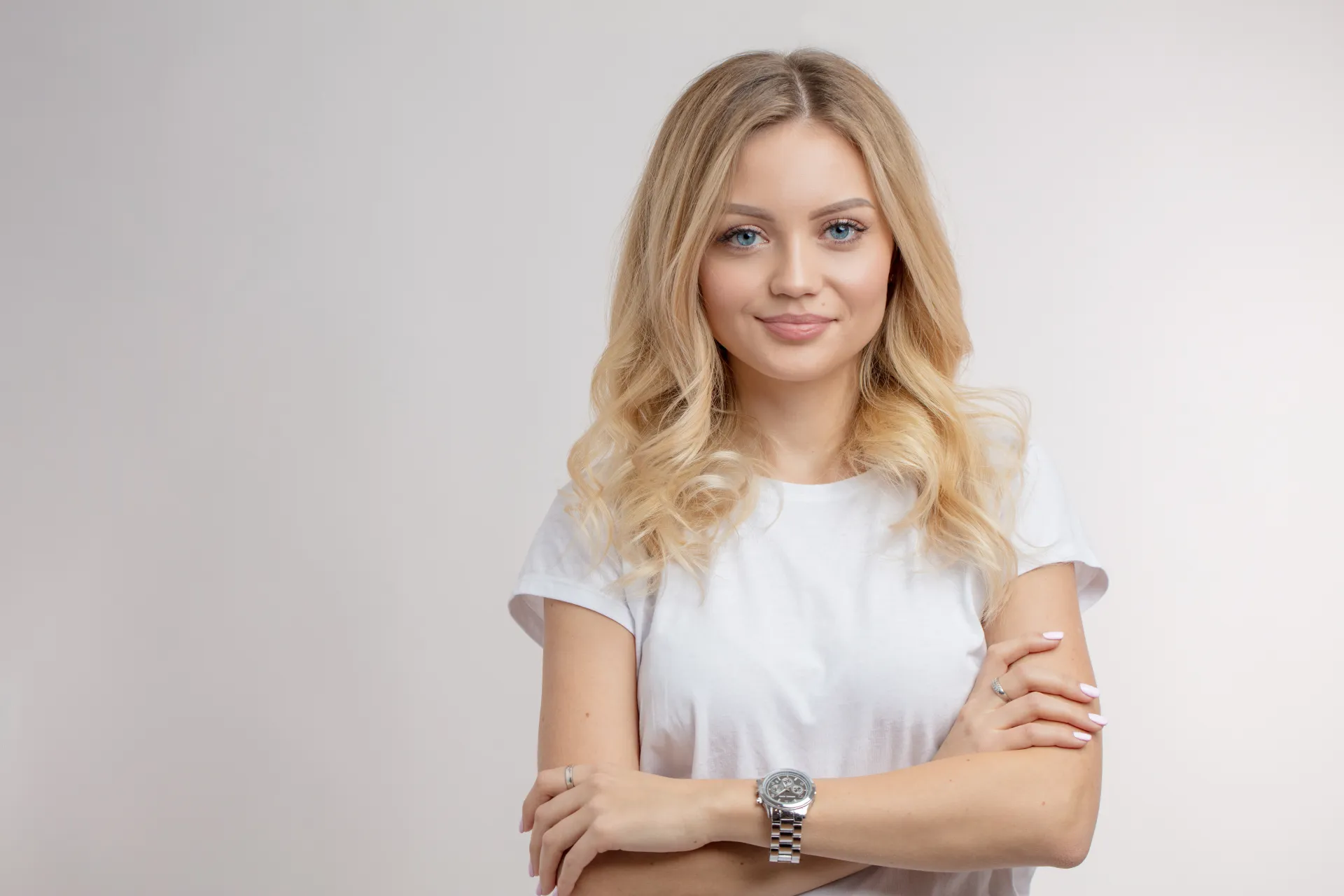 Junge blonde Frau in weißem T-Shirt, Arme gekreuzt
